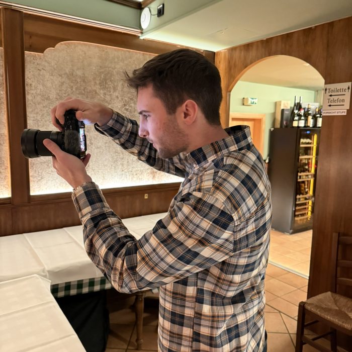 Über uns – Luca von KKM Media blickt durch seine Kamera auf das Display und überprüft das Motiv.